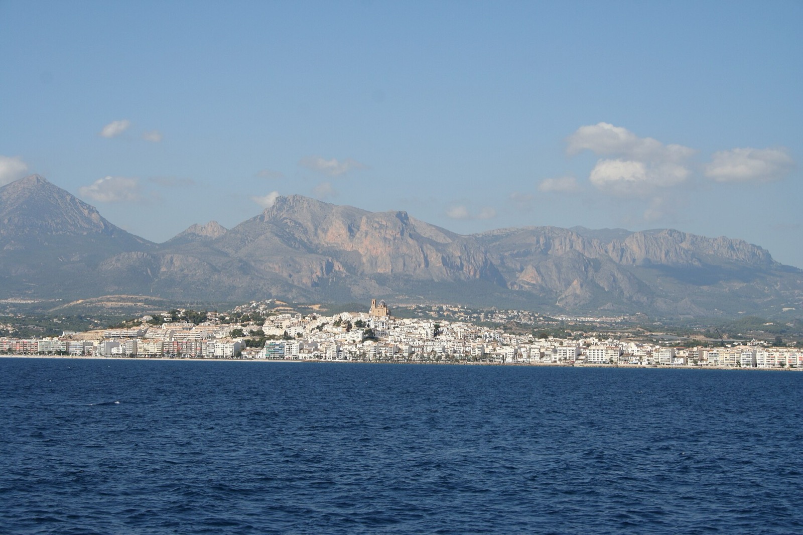 Altea's whitewashed town and church seen from the sea, with mountains behind