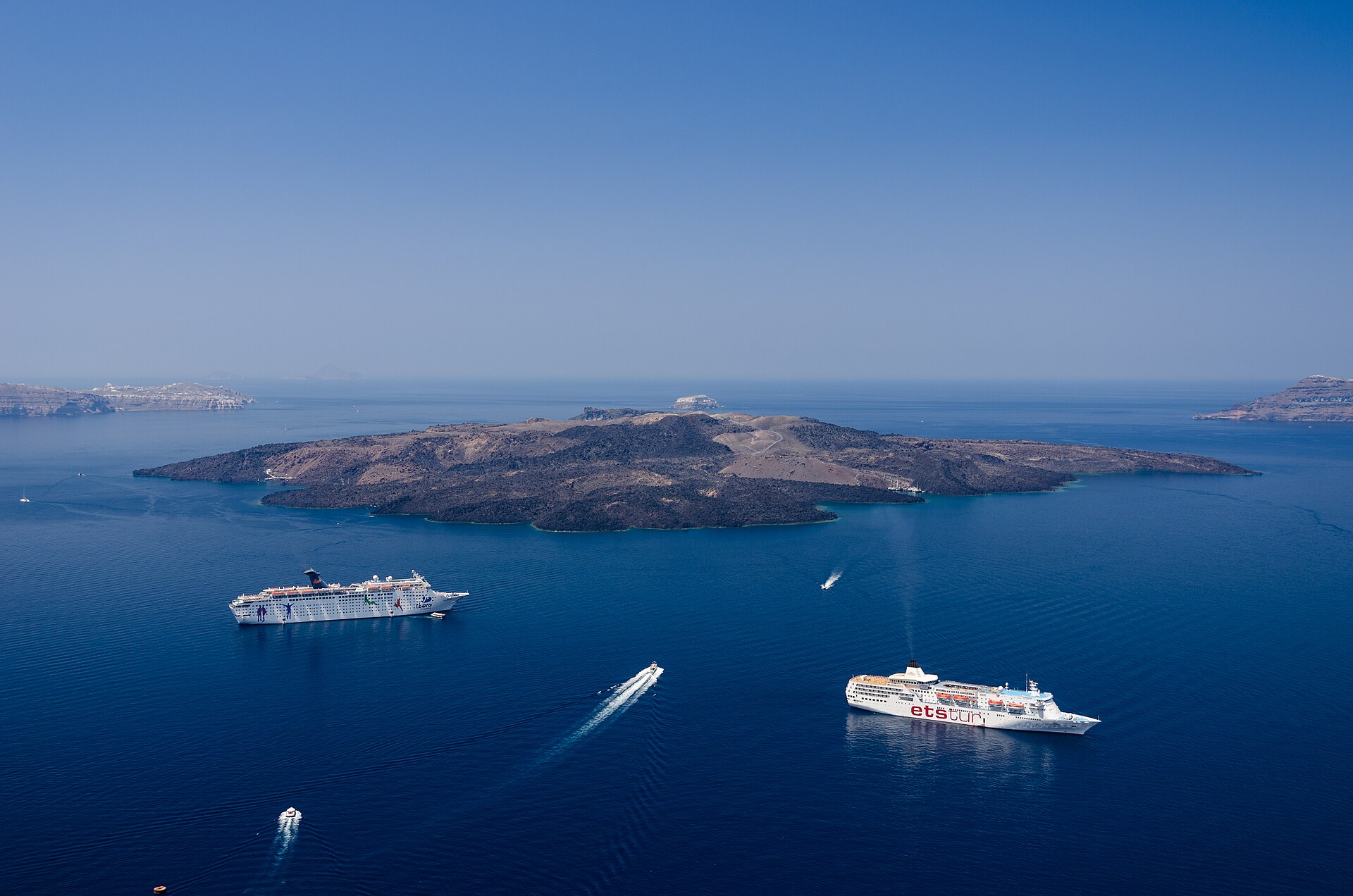 La isla volcánica de Nea Kameni en la caldera de Santorini, vista desde Fira, con barcos en el agua